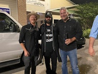 three men standing in front of a van